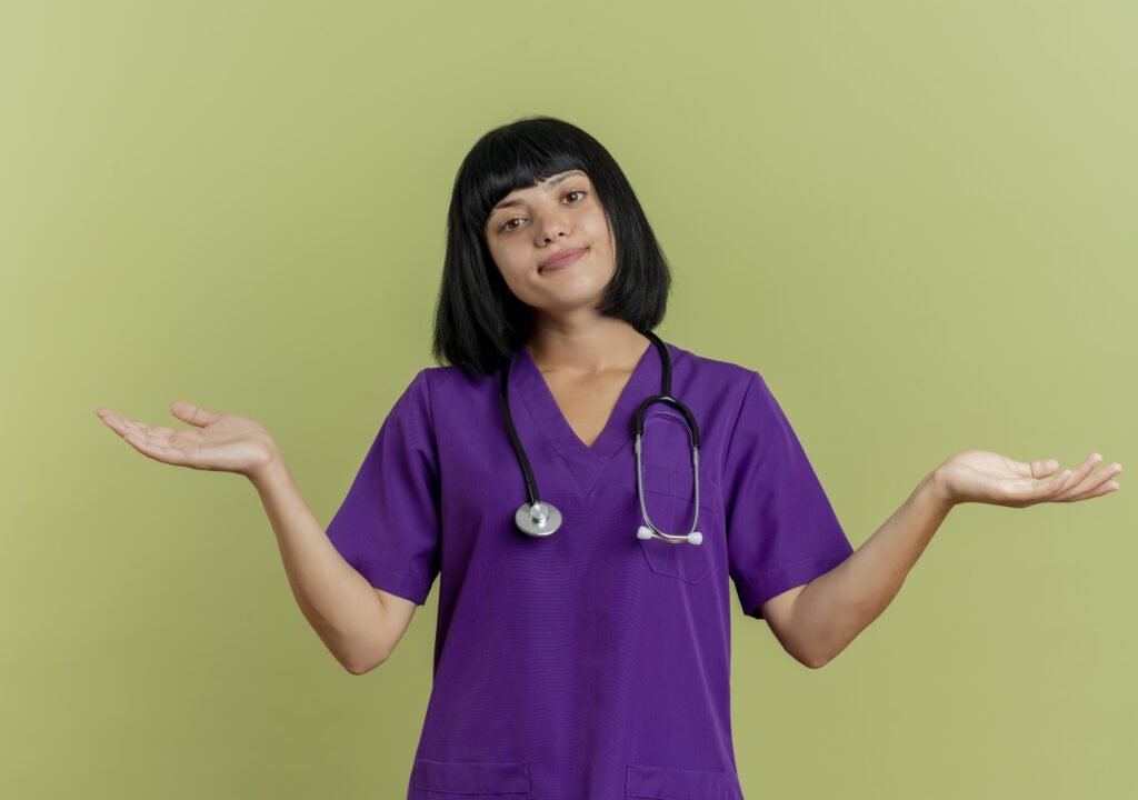 Functional Medicine Doctor in India wearing purple medical scrubs and stethoscope, standing with open hands gesture against green background.